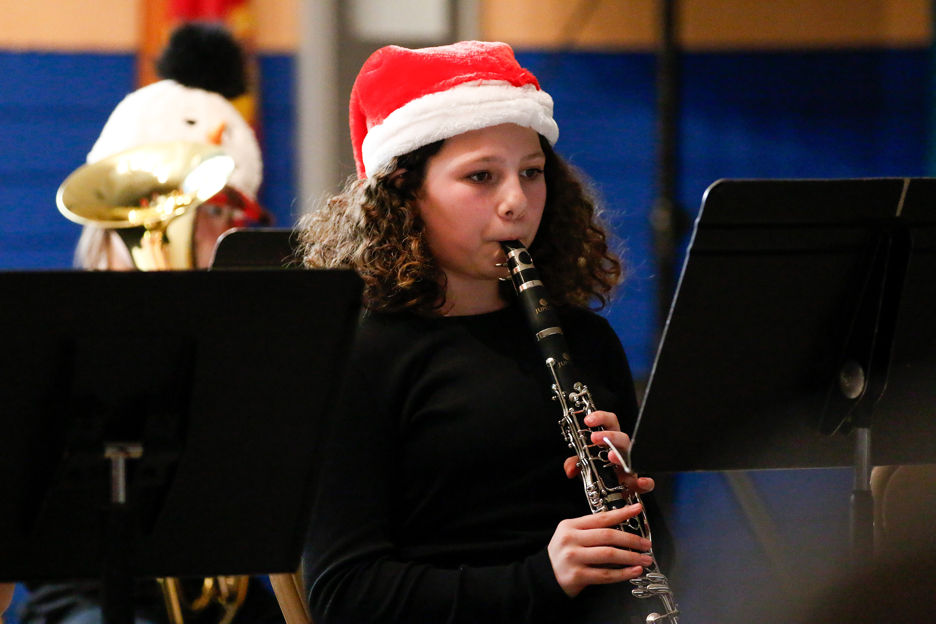 A girl in a Santa hat plays clarinet