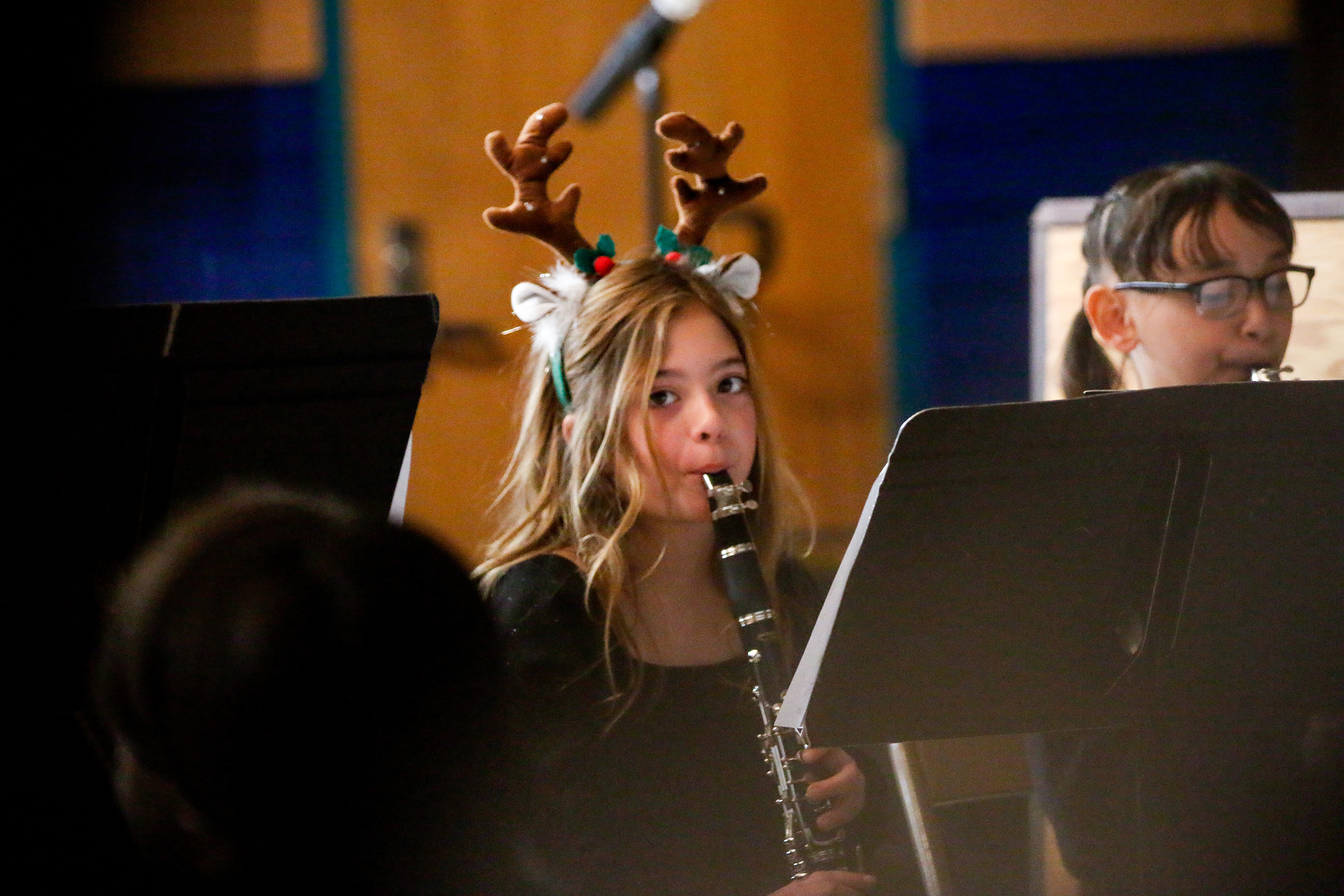 A girl in reindeer antlers plays clarinet