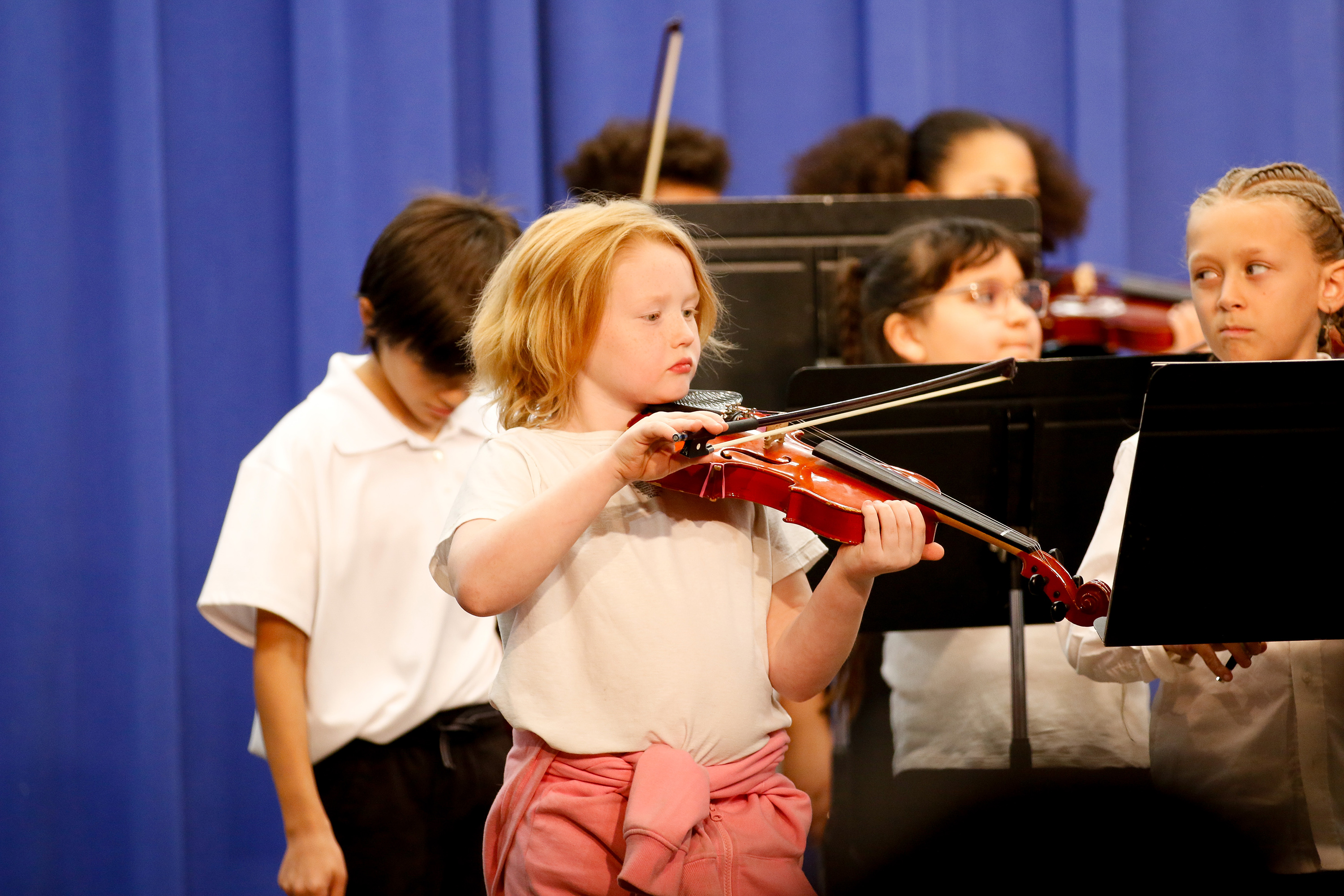 A girl with blonde hair plays violin