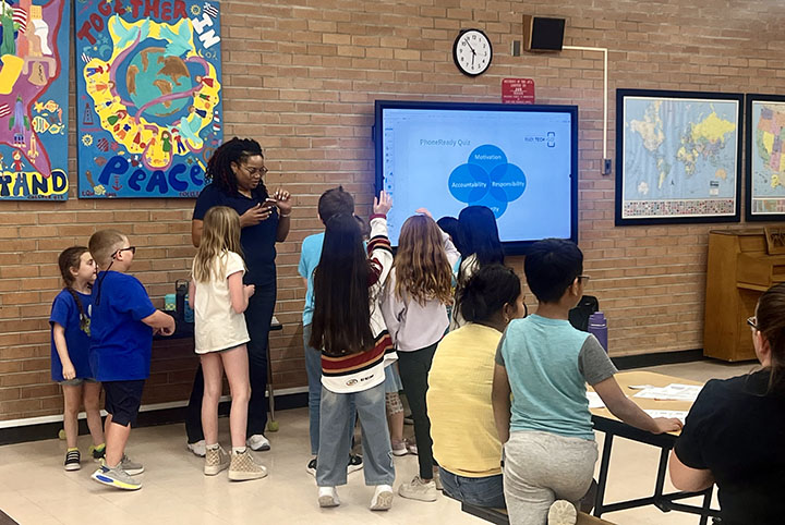 Students stand around a smart screen