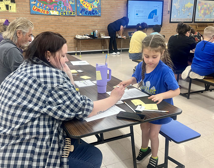 A woman and a little girl work on an assignment at the cafeteria table