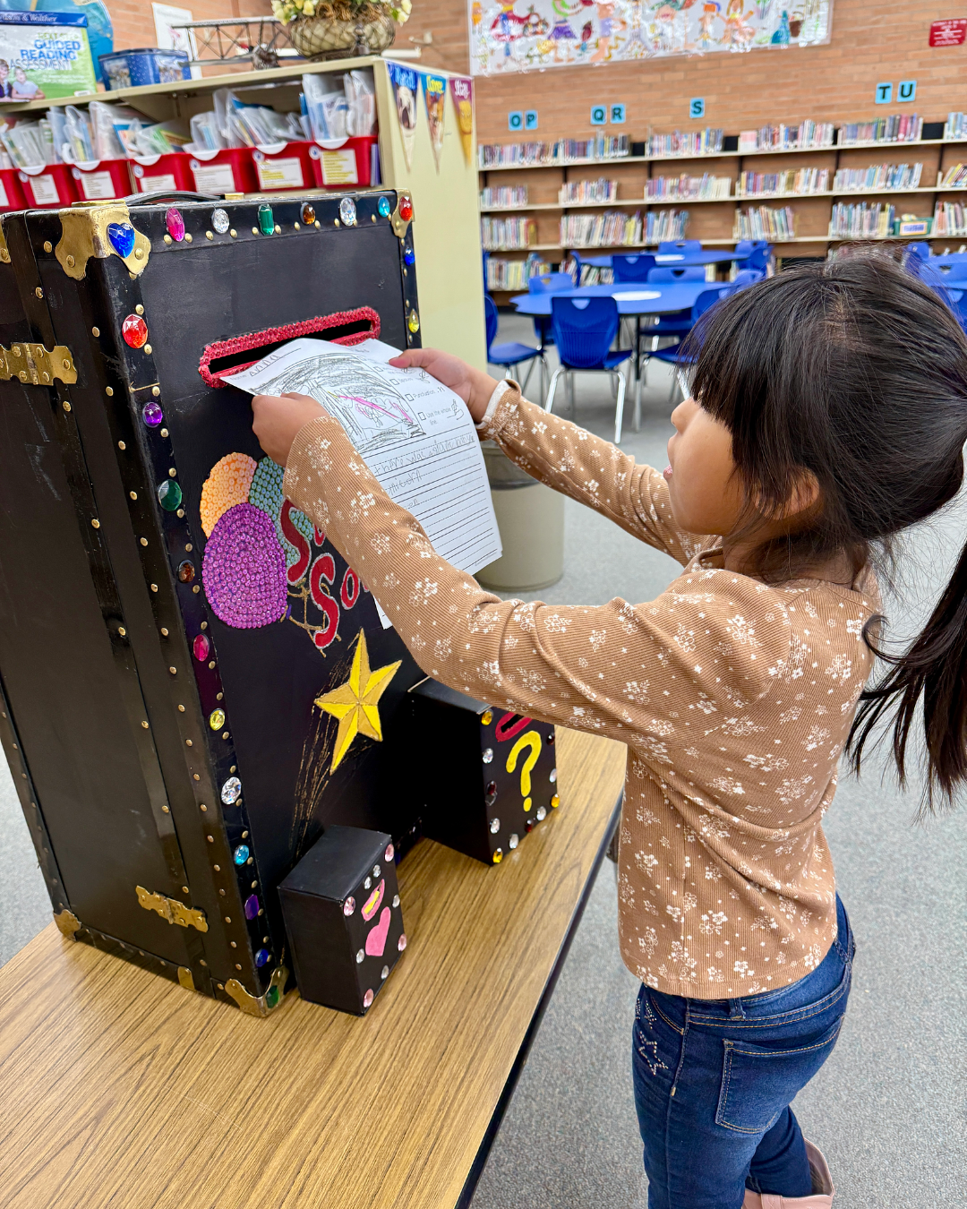 A little girl puts a piece of paper into the Magic Box