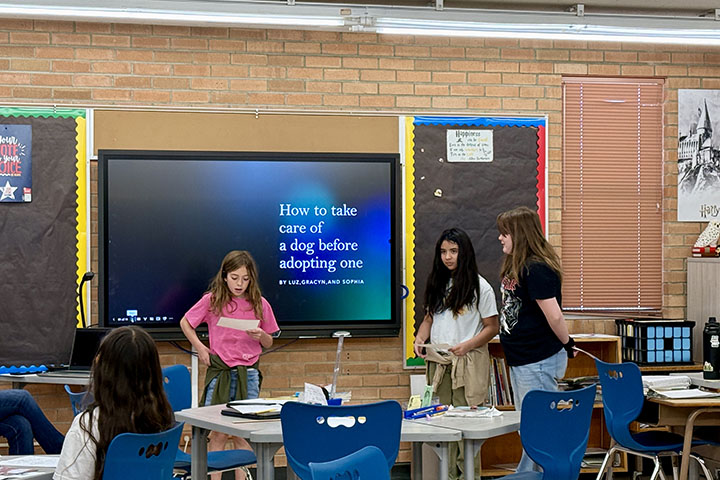 Three girls deliver a presentation about how to take care of a dog before adopting one