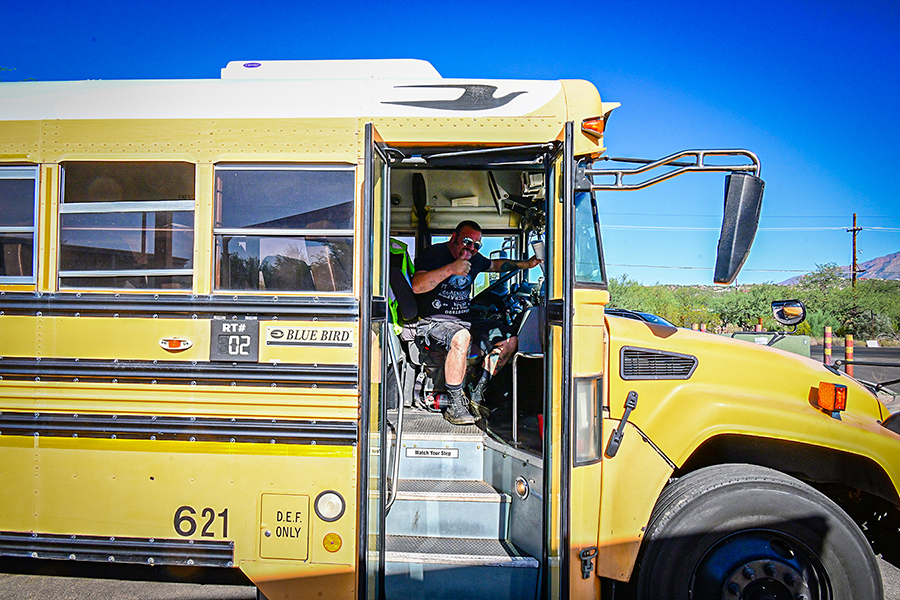 A bus driver gives a thumbs up from inside his school bus