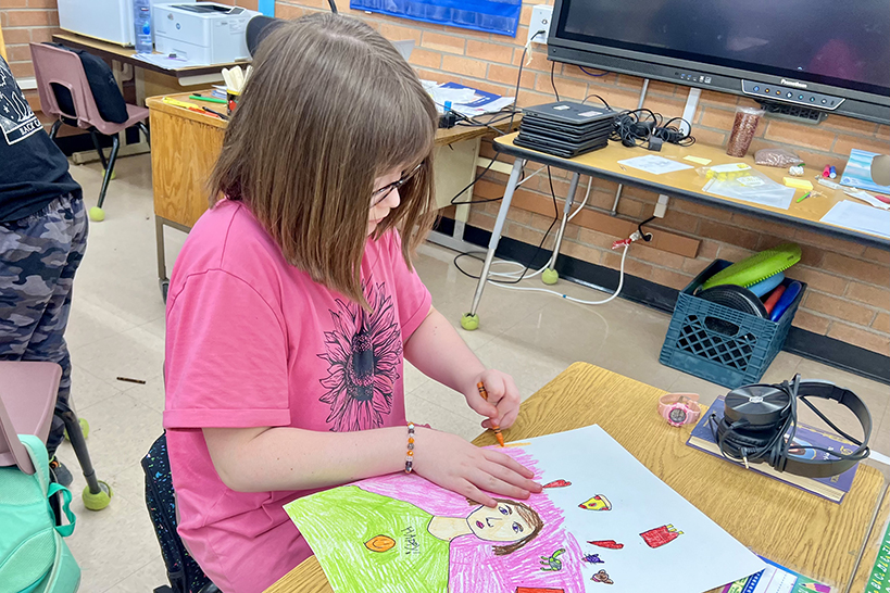 A little girl draws a self-portrait