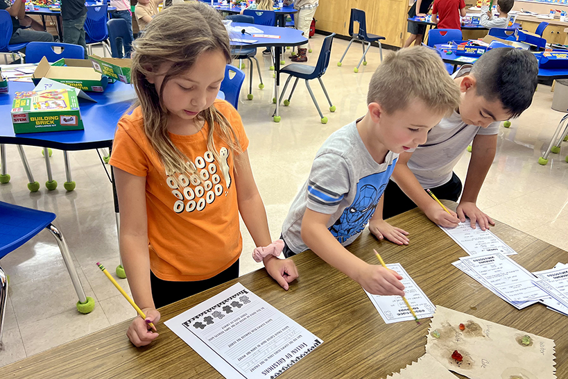 A little girl and boy write on worksheets