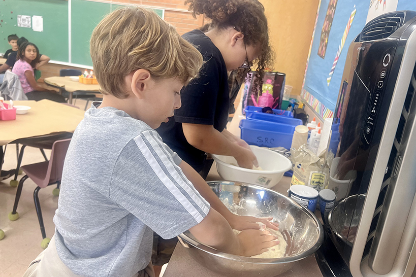 A boy kneads the dough for his masa in a silver bowl