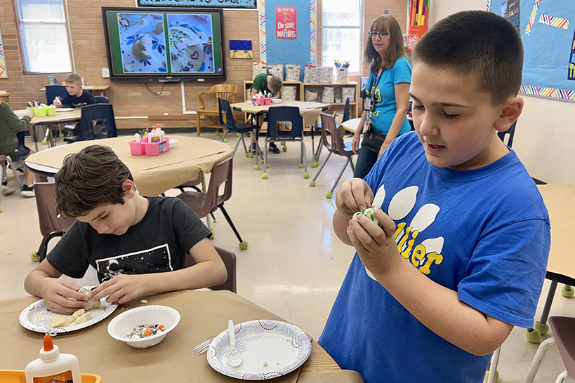 Two boys work on their masa dough sculptures