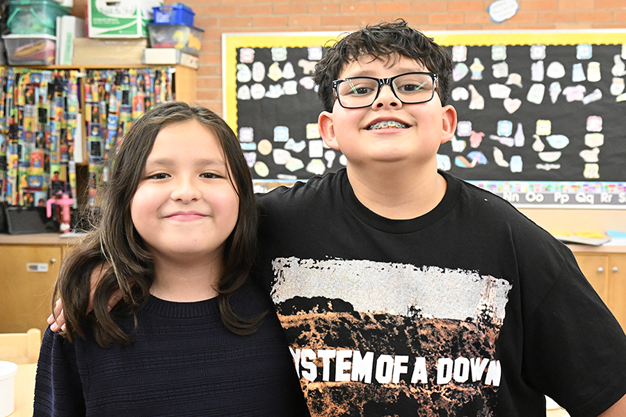A girl and a boy smile in a classroom