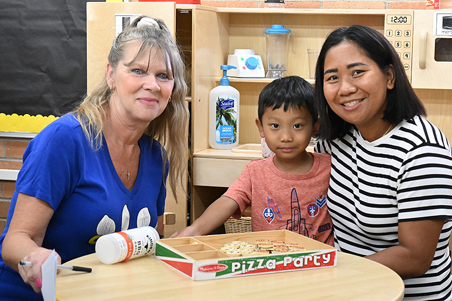 A boy and his mom pose with his new teacher
