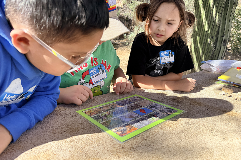 Three students look at a photo of desert wildlife
