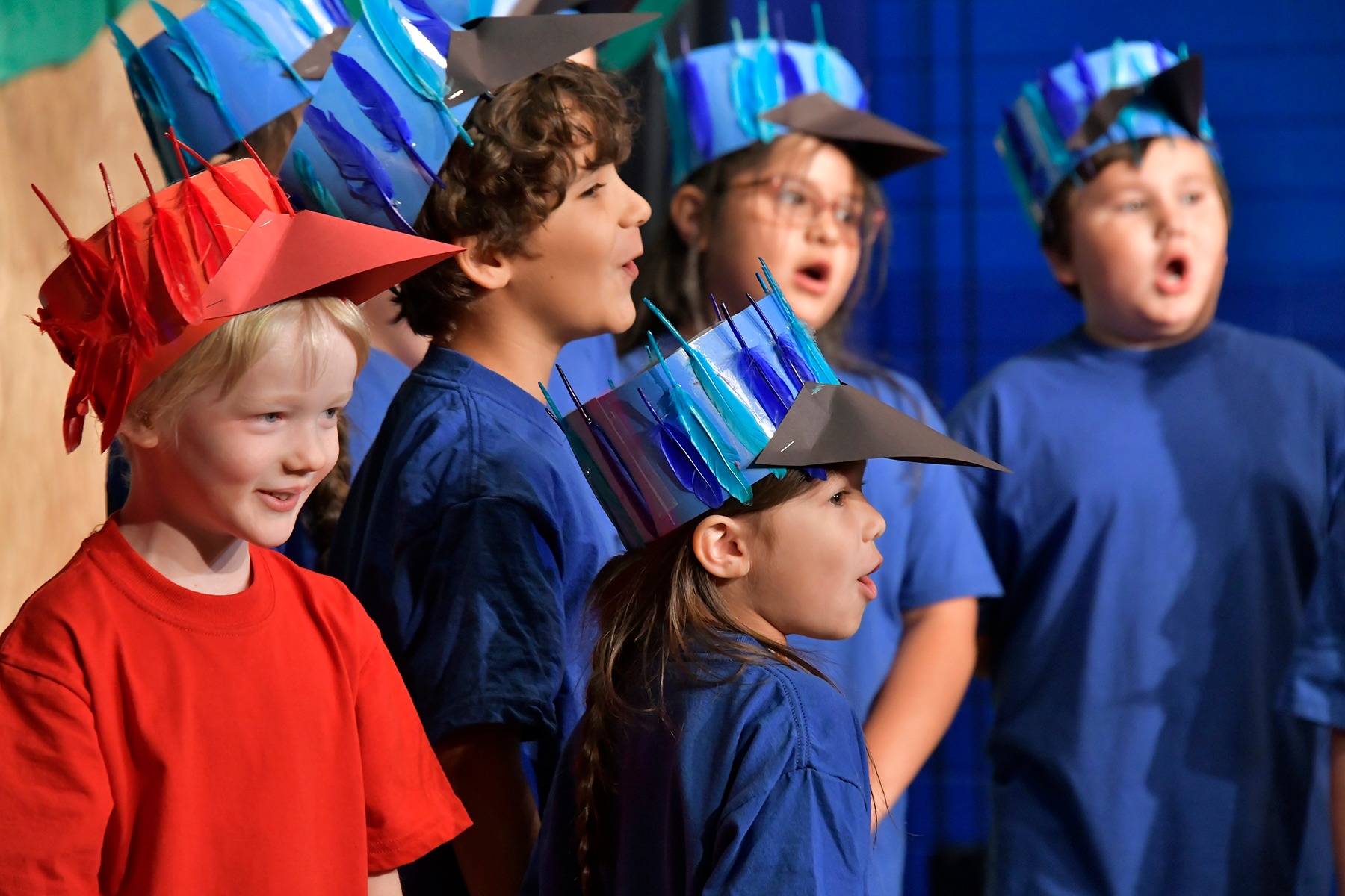 Collier students in blue and red costumes sing during their OMA performance